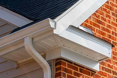 close up of off-white k-style gutters on brick house